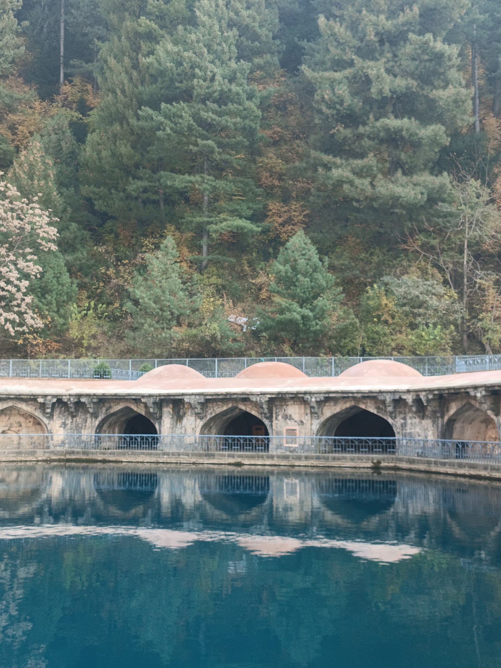The historic octagonal pool of Verinag surrounded by stone arches and chinar trees.