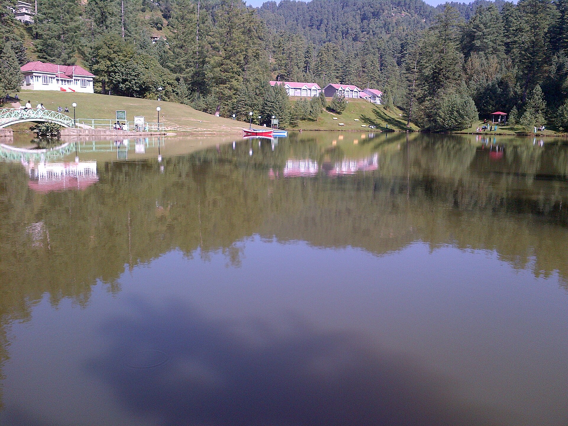 A traditional Kashmiri guest house set among green trees near water