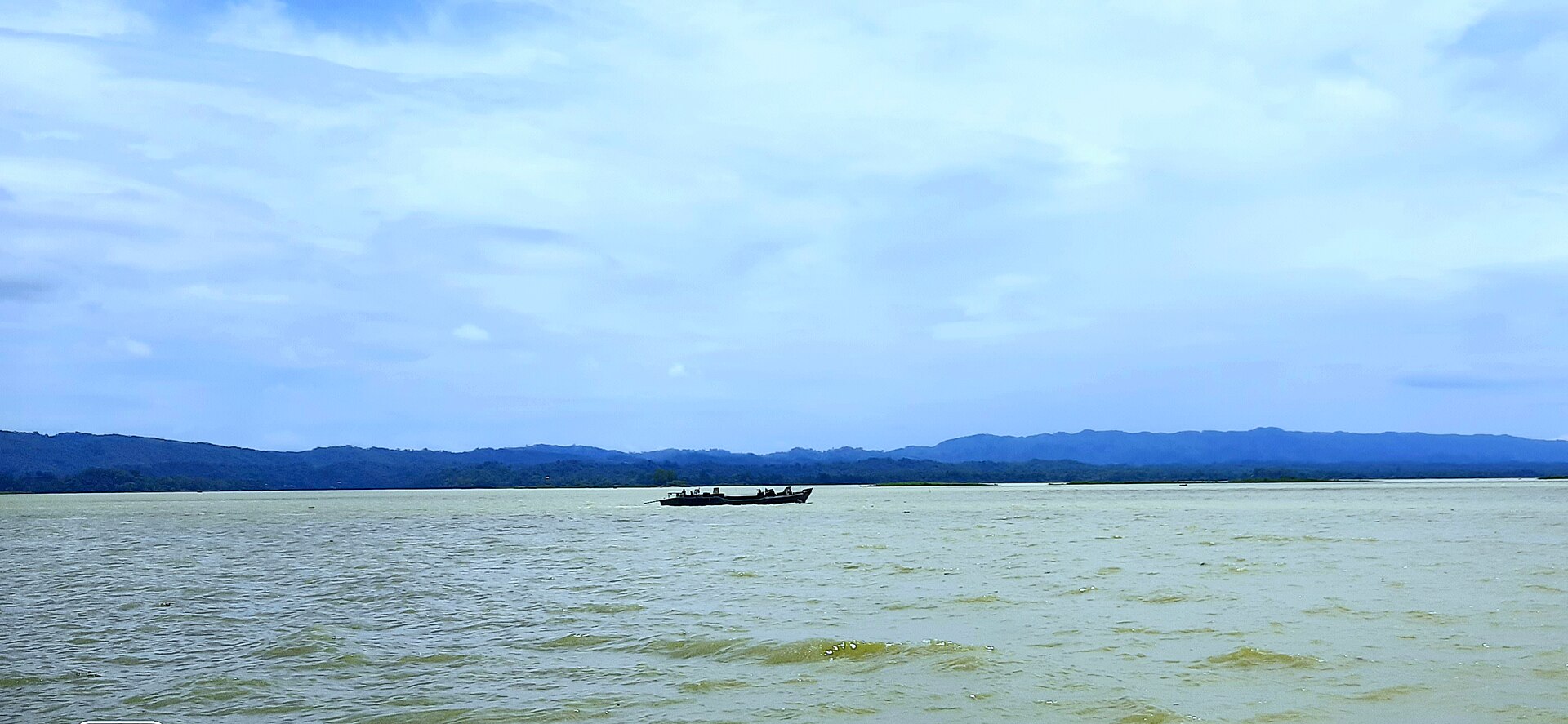 A wooden fishing boat gliding across the expansive surface of Wular Lake