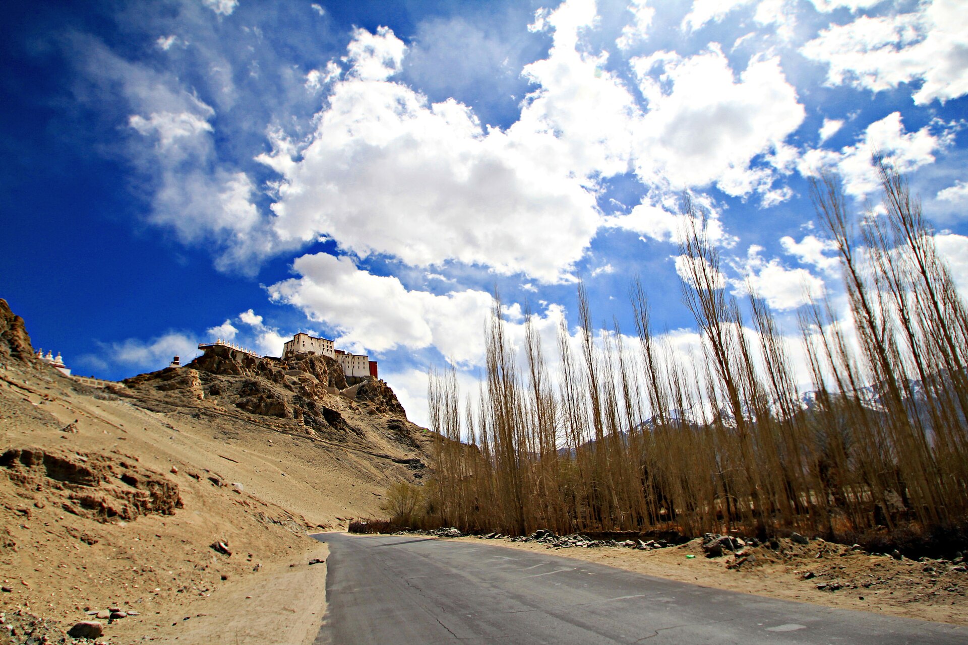 A sturdy 4x4 SUV traveling through a dusty, rocky valley in Ladakh.