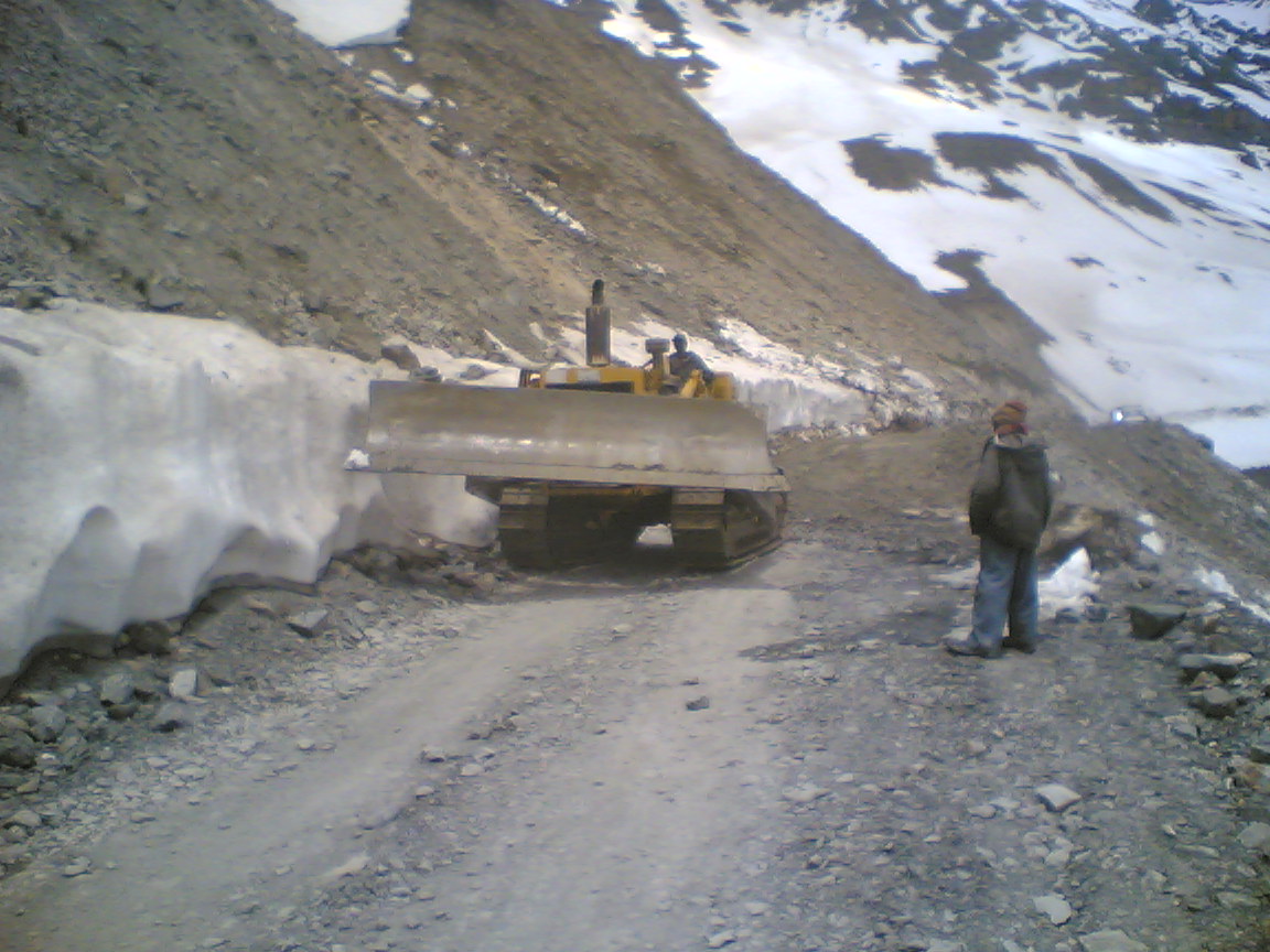 A winding, unpaved road climbing up a dramatic mountain pass.