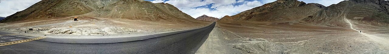 Winding asphalt hairpin bends climbing steeply up a barren mountain slope in Ladakh