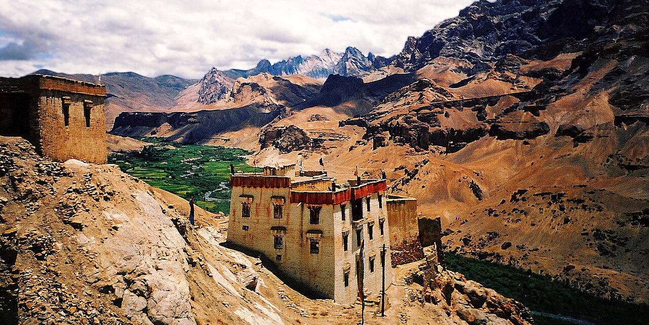 Green oasis village surrounded by dry brown desert mountains and the Indus river