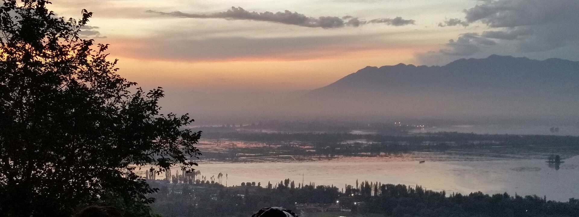 An aerial view showing the vast expanse of Dal Lake and the surrounding mountains.