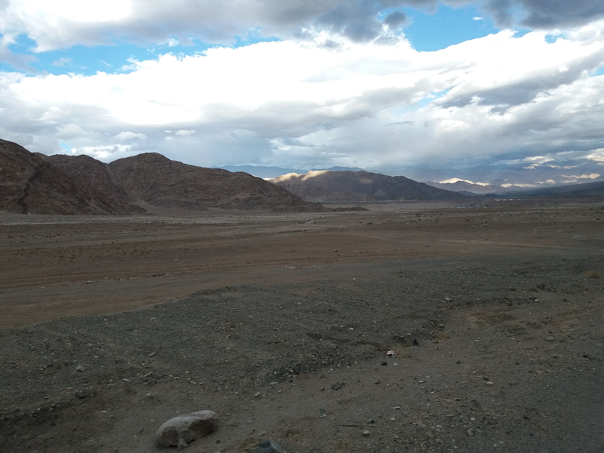A long, winding highway stretching through a barren mountain valley.