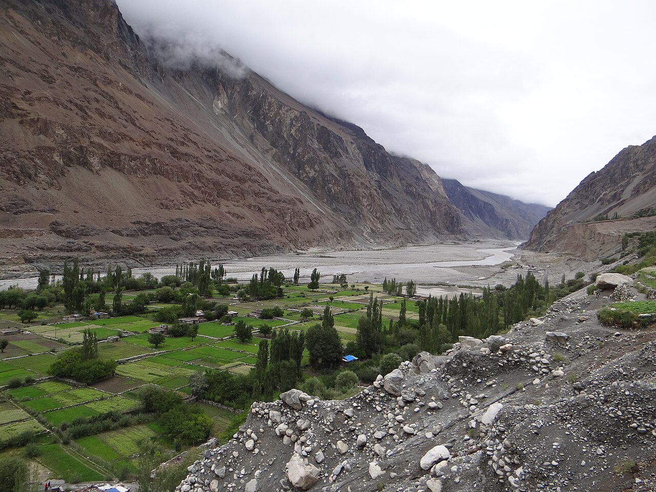 The grey, fast-flowing Shyok river with rocky cliffs.