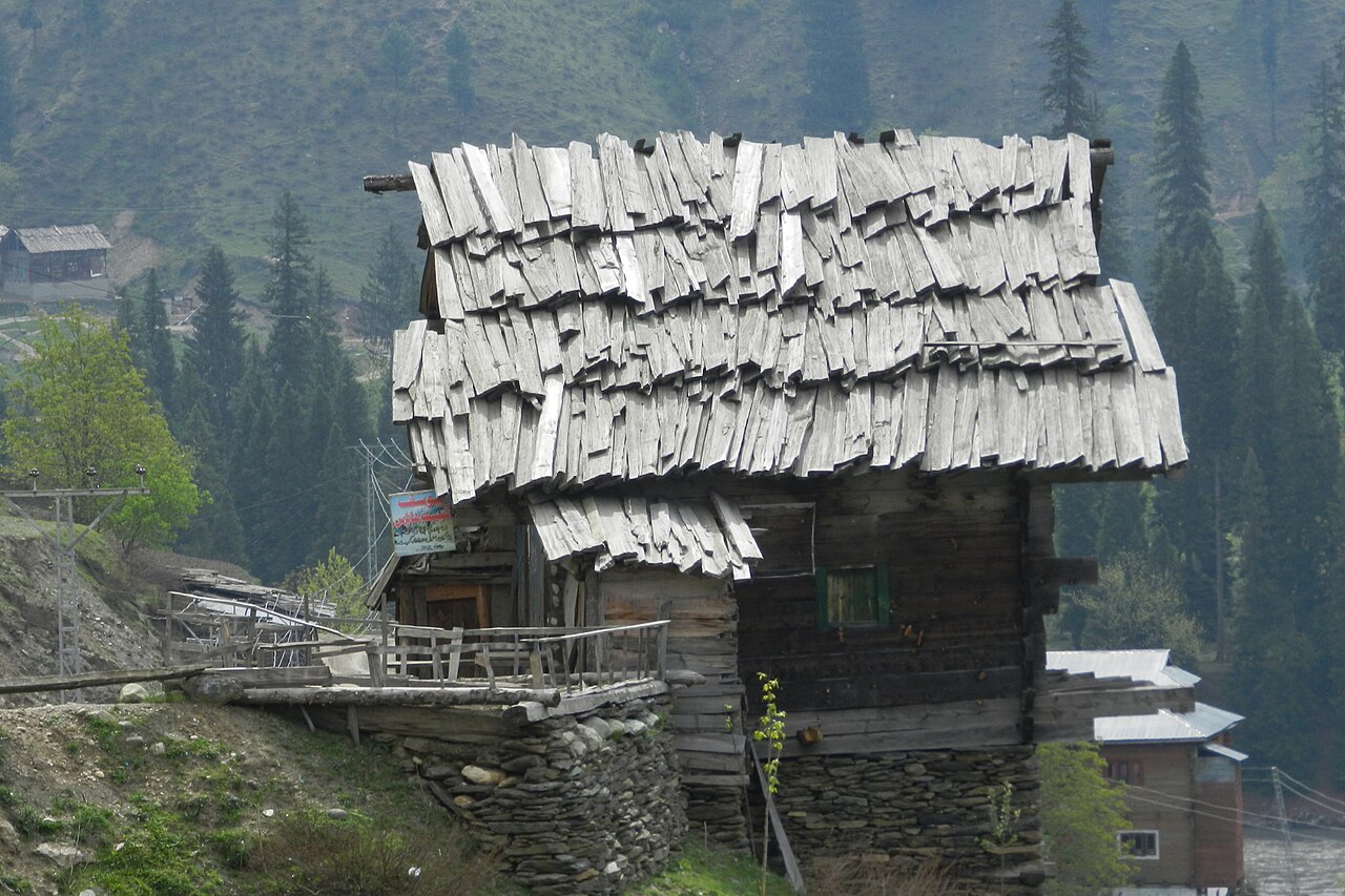 A rustic wooden mountain home with stone foundation in a valley village