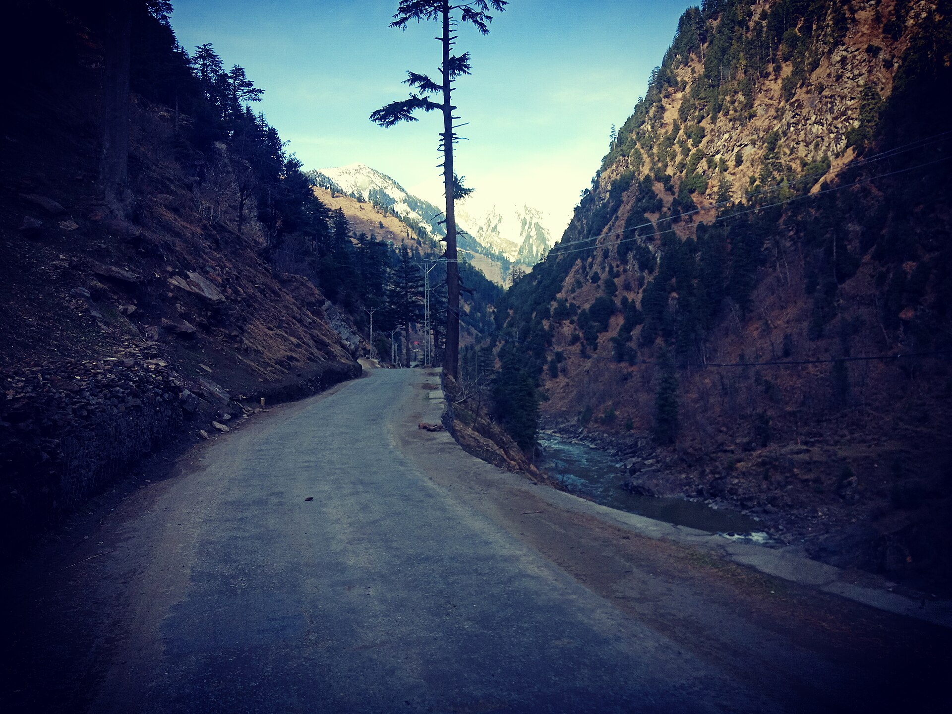 Mountain highway winding through green hills with distant security presence