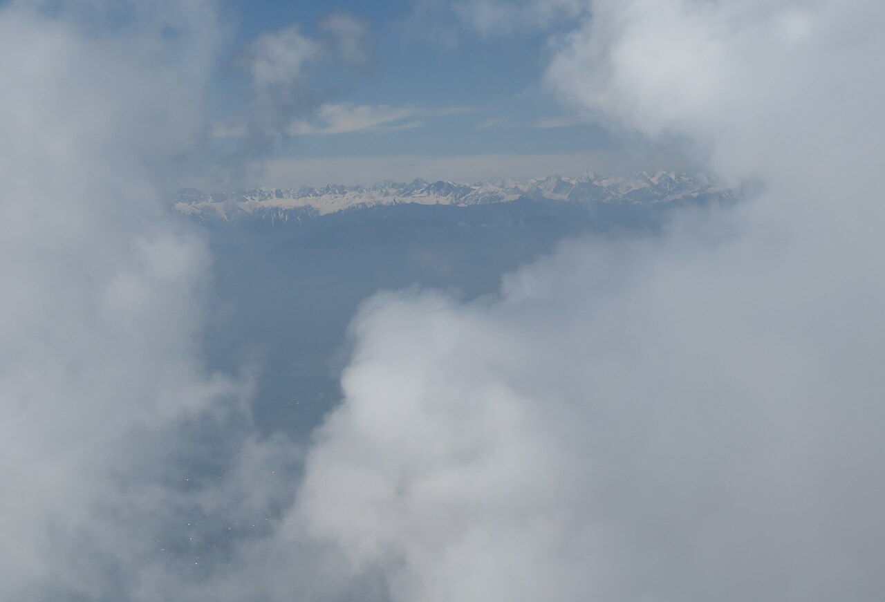 Cabin of the Gulmarg gondola system rising toward the snowy mountains.