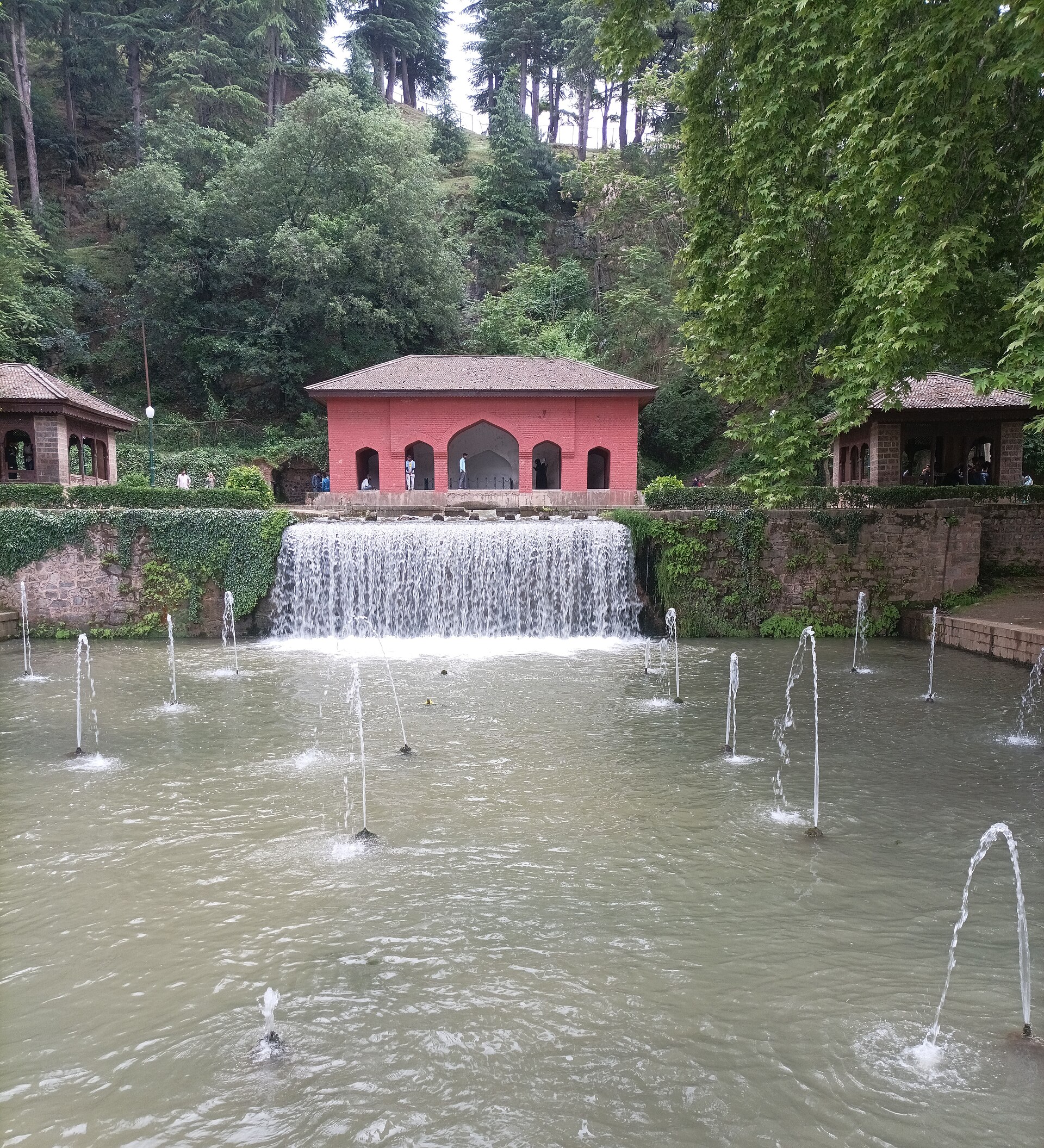 Restored stone and brick pavilion structure within a Mughal garden