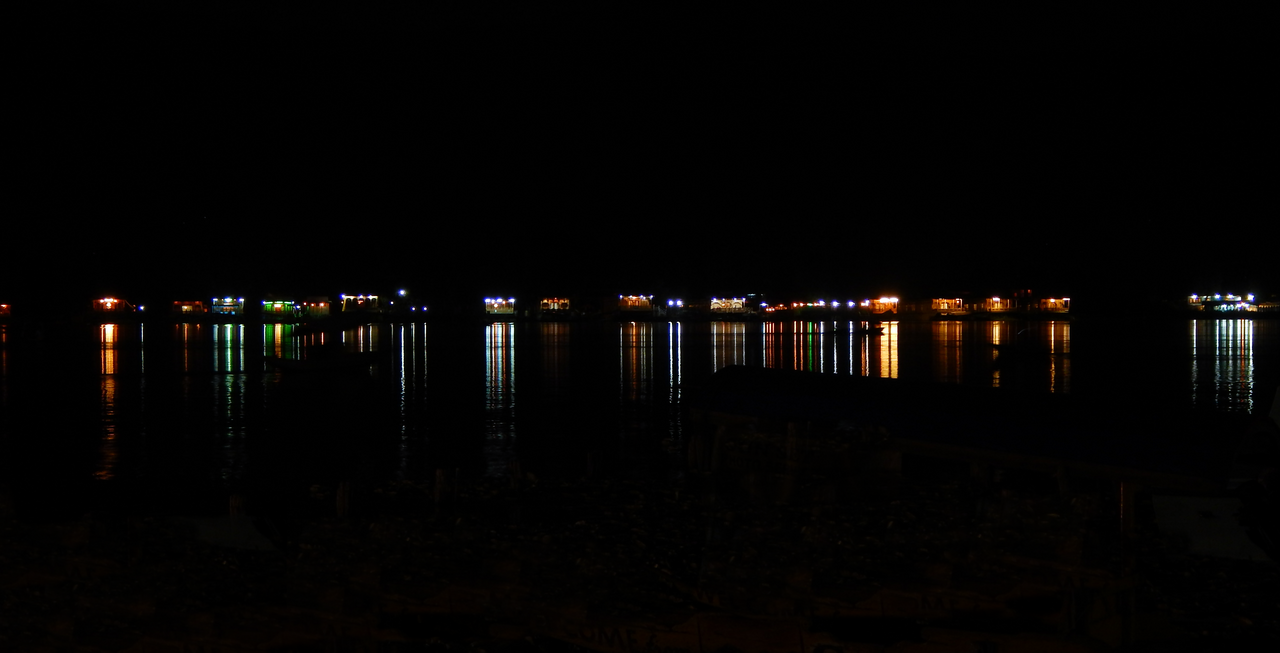 Lights from houseboats reflecting on calm lake water at night