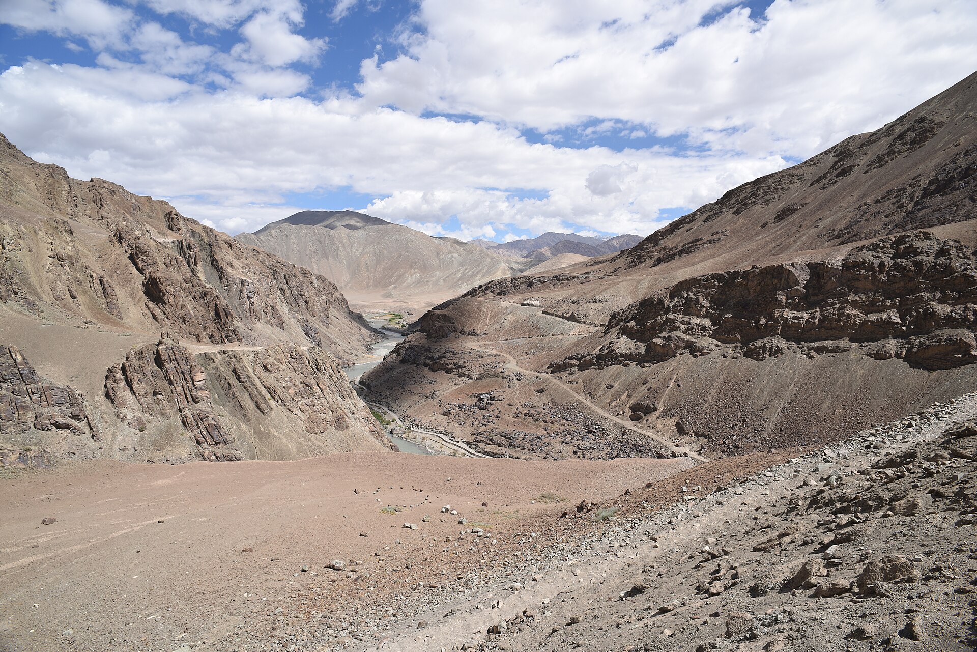 Winding dusty road cutting through barren mountain slopes in Spiti Valley