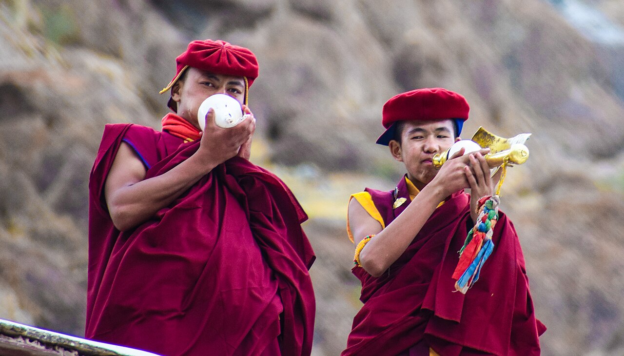 Buddhist monk playing a long copper horn during a festival in Ladakh