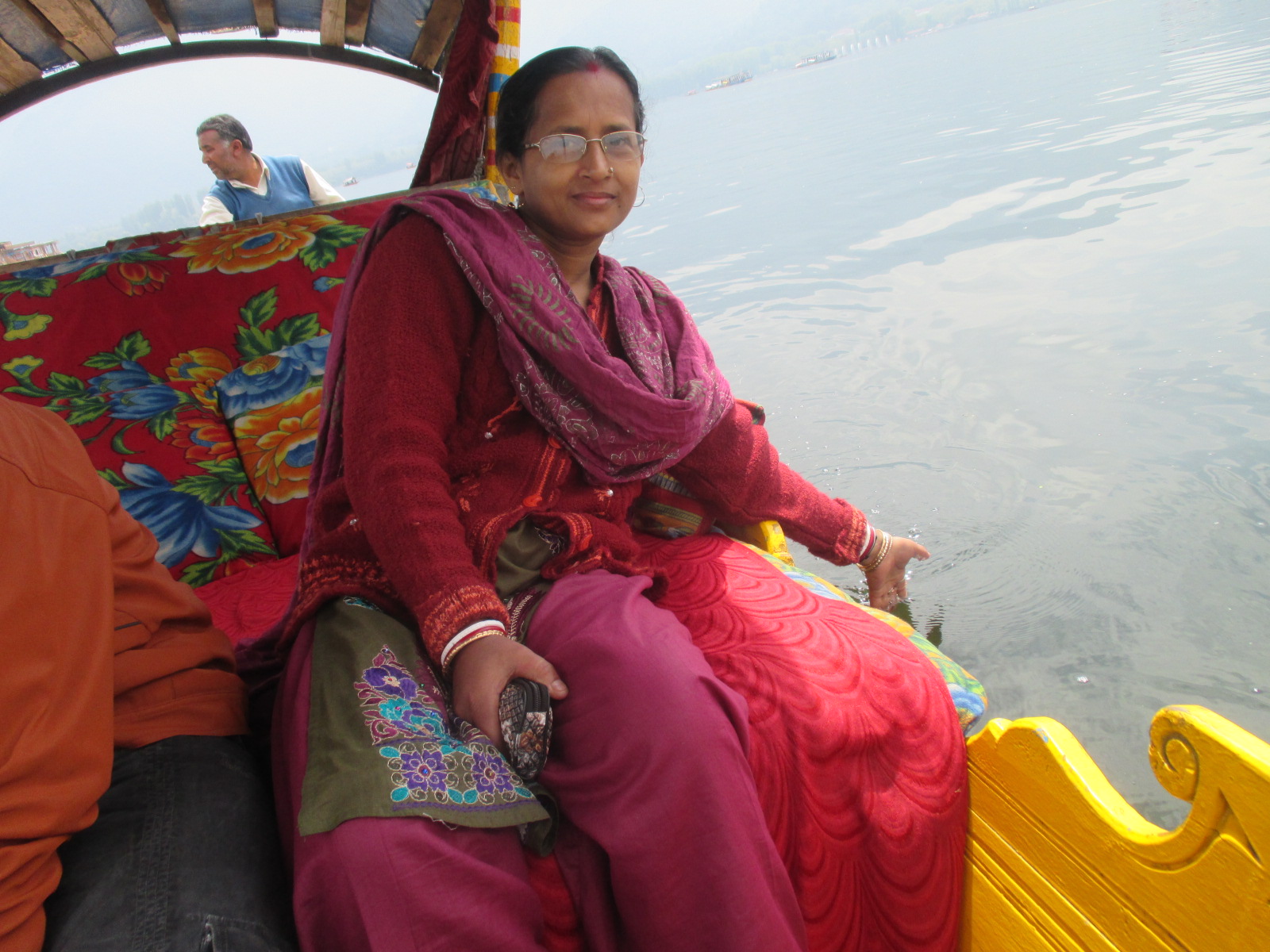 A traditional wooden shikara boat floating on the calm waters of Dal Lake during sunrise.