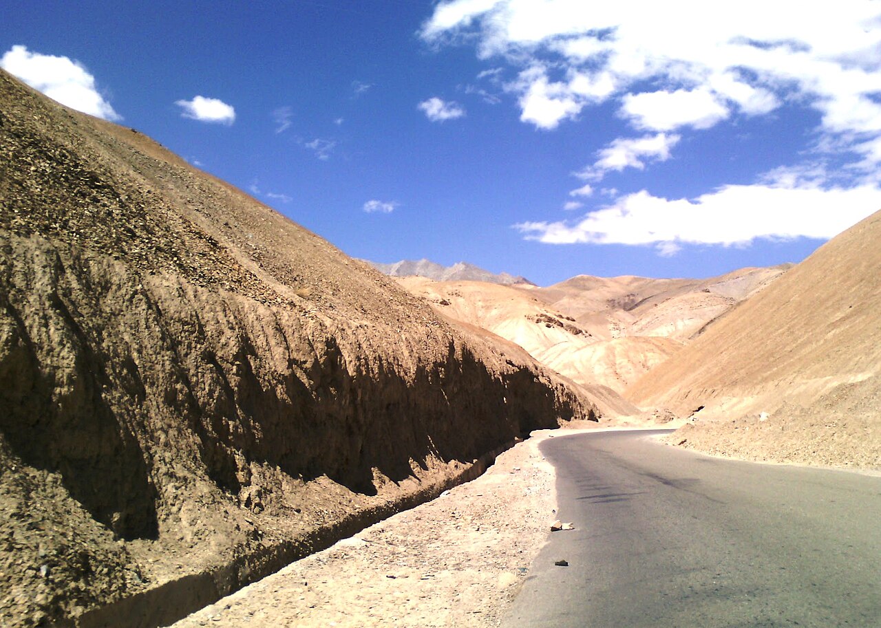 A dusty road winding through high altitude mountains