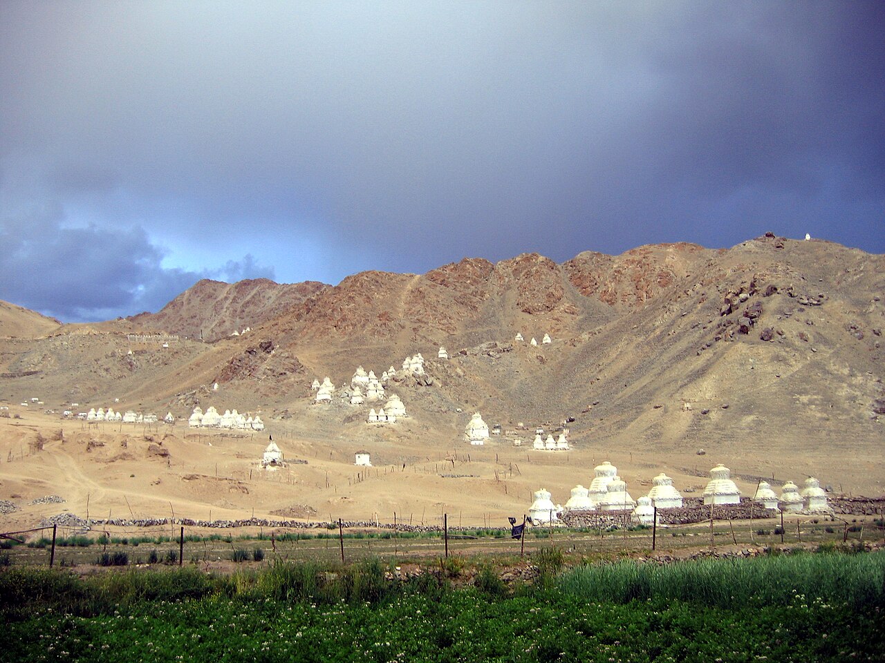 A stone mani wall with carved mantras in a mountain valley.