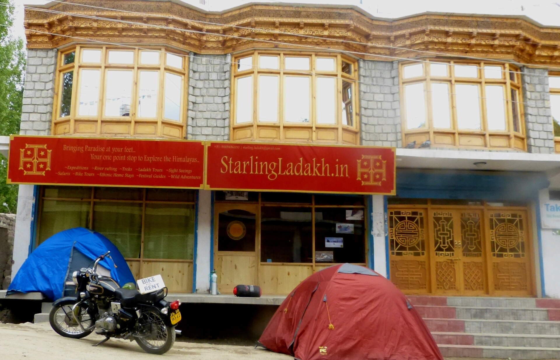Travel agencies and shops lining a sunny street in Leh market
