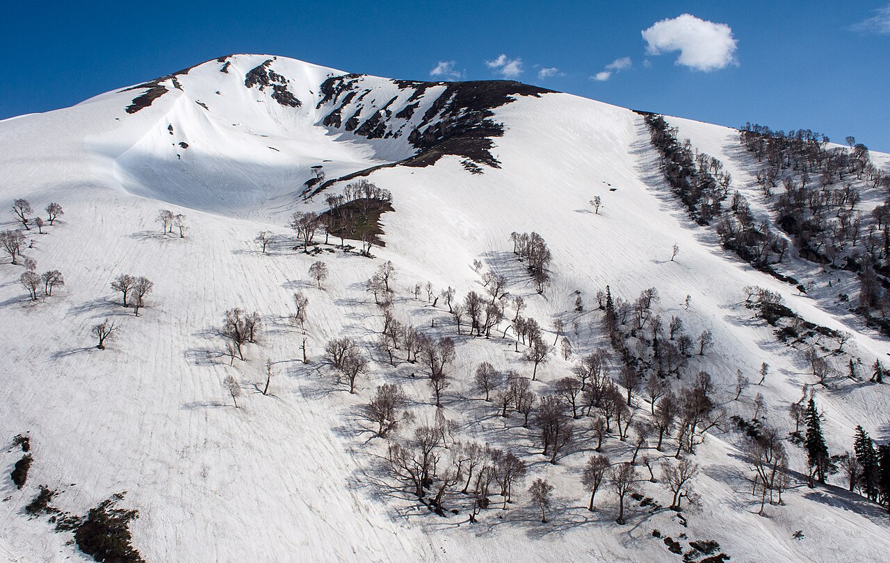 A small patch of white snow on a rocky mountain slope in summer